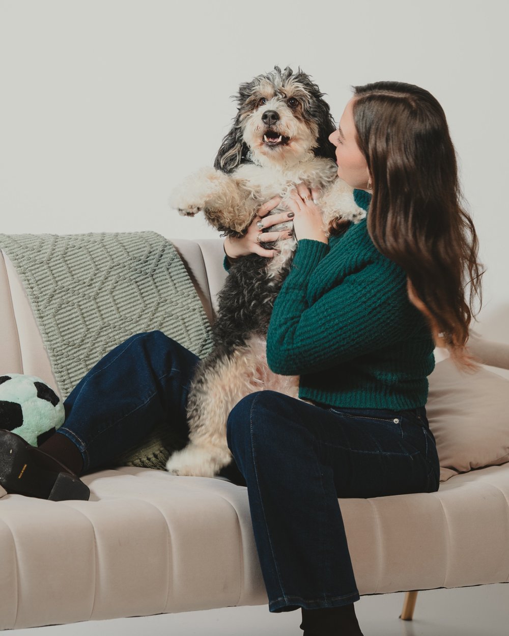 Nicole lifting her dog for a hug on the sofa