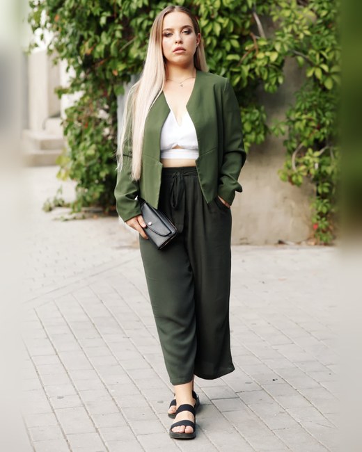 A relaxed olive jacket and wide-leg trousers with a white top and flat sandals, an example of the Sporty / Natural style