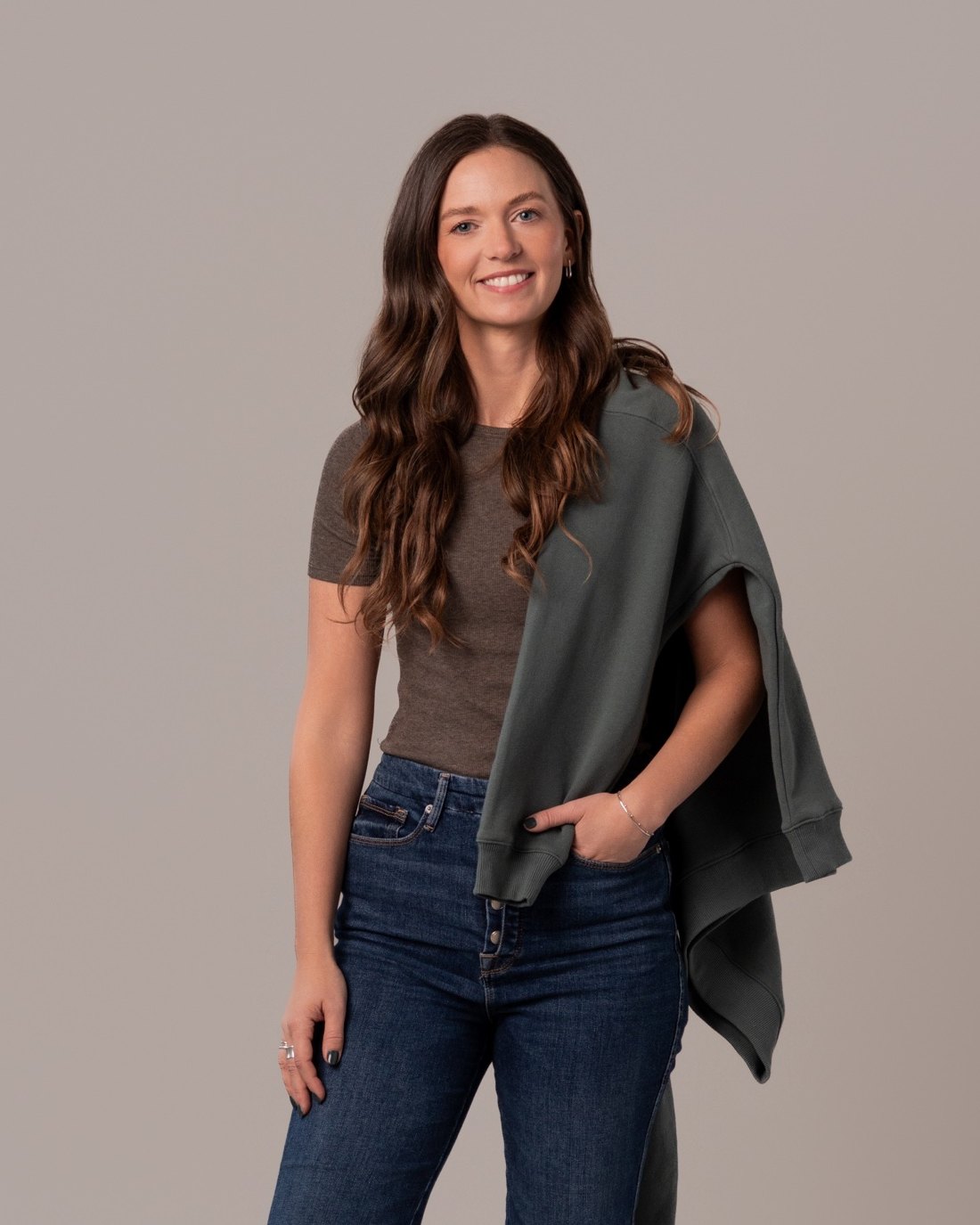 Nicole, founder of The Stylery Colour Studio and color analysis trainer, in jeans with a green sweater over her shoulder