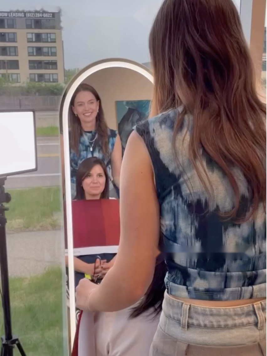 Nicole and a guest smiling in the mirror while another guest is draped in red at a color party